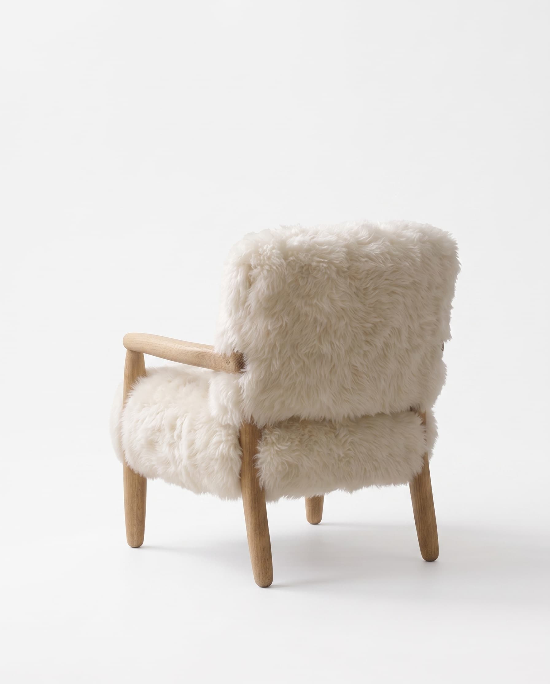 Fauteuil Arosa vu de dos — dossier habillé de peau lainée sur structure bois